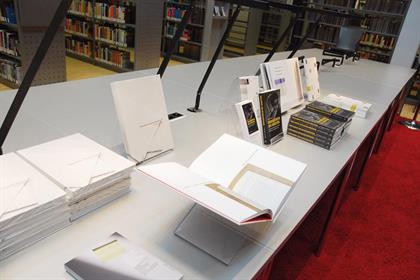 Bücher, die Rahmen der Ausstellung präsentiert wurden, liegen ansprechend drappiert unter einer Leselampe.