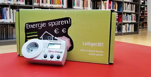 Foto: Ein Strommessgerät liegt auf einem Tisch, dahinter steht die Verpackung.